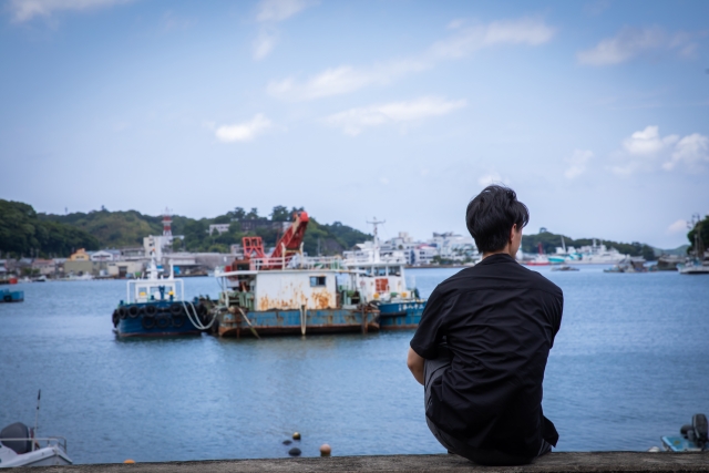 海で遠くを見つめる男性